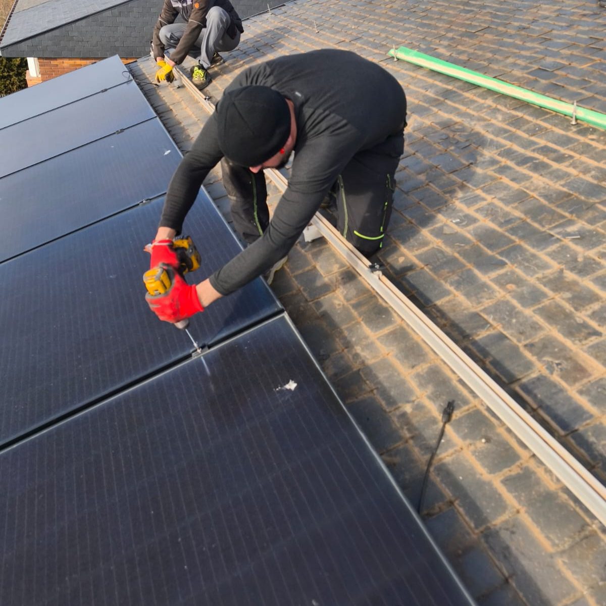 Trabajador ajustando paneles solares durante una rehabilitación en Colmenarejo